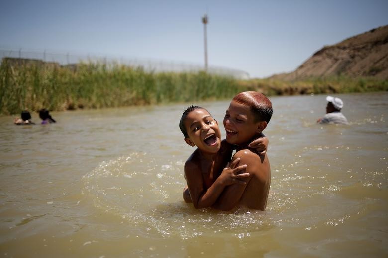 Children cool off during a hot day on the Mexican side of the Rio Bravo near the fence marking the border between Mexico and the U.S, as pictured from Ciudad Juarez, Mexico. REUTERS/Jose Luis Gonzalez  